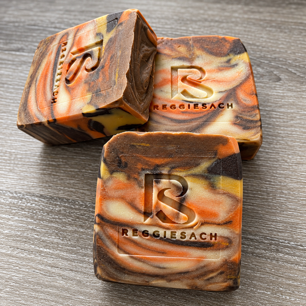 ReggieSach Pumpkin Pickin' Bar Soap, three marbled bars in orange, brown and cream swirls on a grey wood surface, embossed ReggieSach logo
