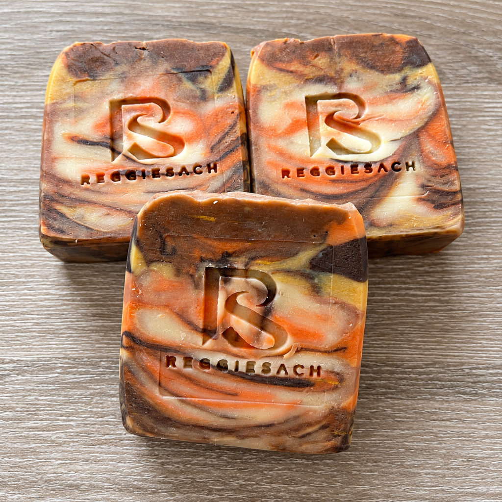 ReggieSach Pumpkin Pickin' Bar Soap, a cluster of three orange, brown and cream marbled bars on a wood grain surface
