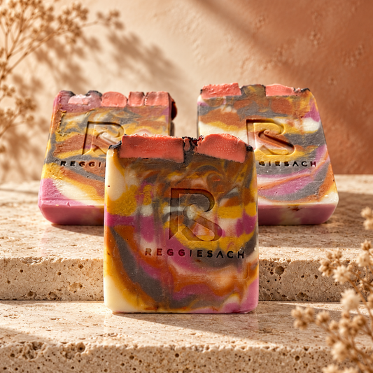 ReggieSach Harvest Sunset Bar Soap in soft-focus depth of field on beige travertine, pink, purple and mustard swirls with textured top inclusions
